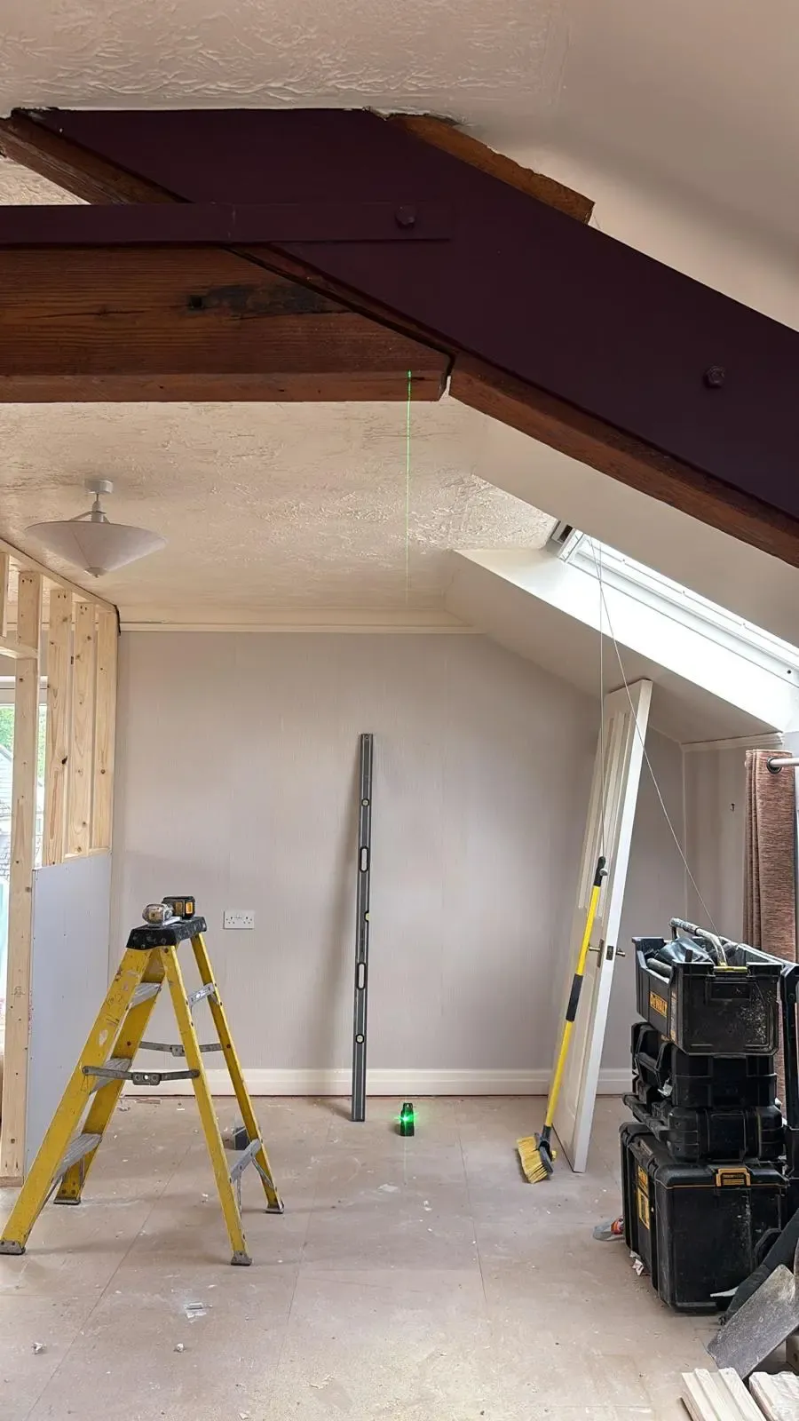 Expert structural alterations in progress during a premium Cotswolds property renovation, showing a laser level aligning structural steelwork with exposed heritage timber beams.