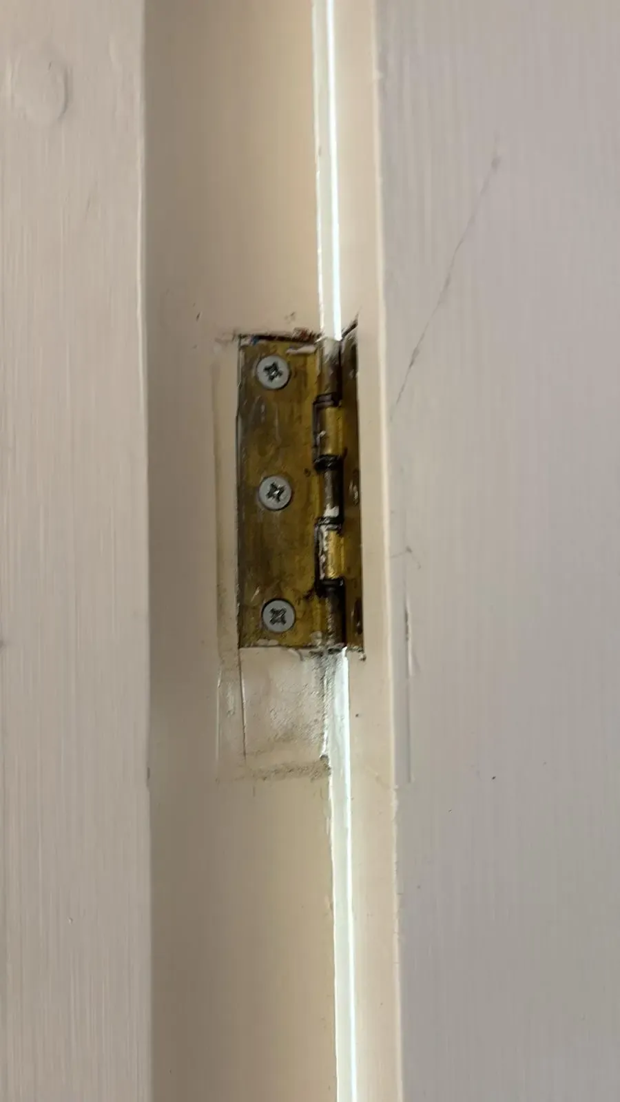 Close-up of an old door hinge on a white painted frame, highlighting the need for premium bespoke joinery and renovation work